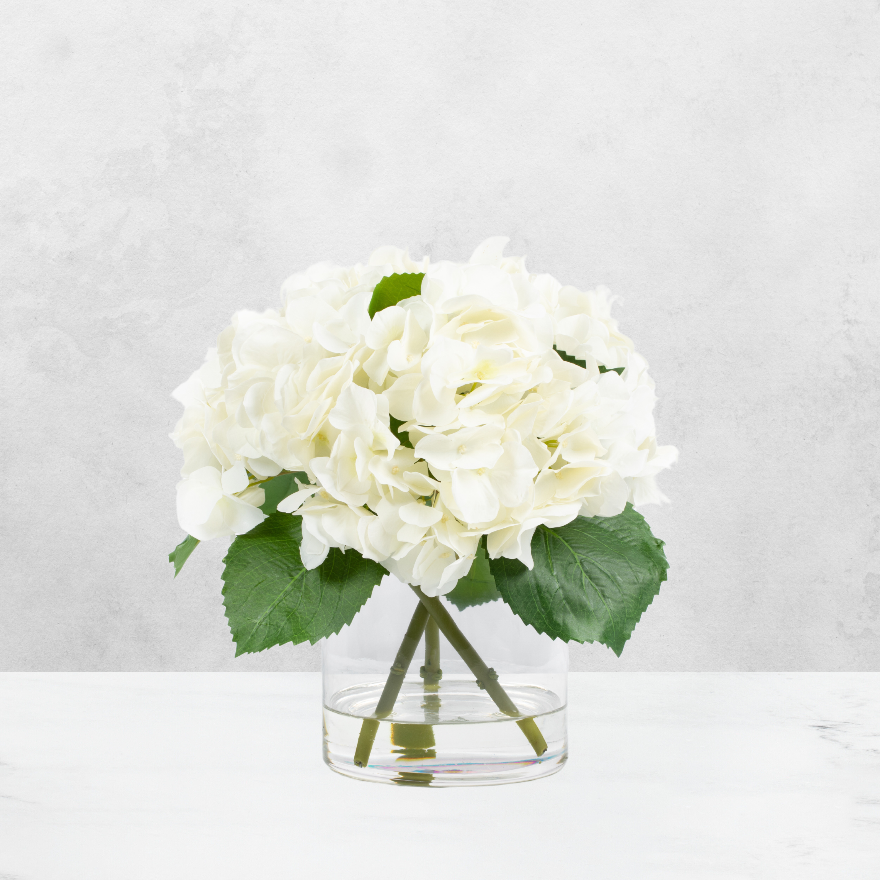 Faux hydrangea centerpiece arrangement in glass vase